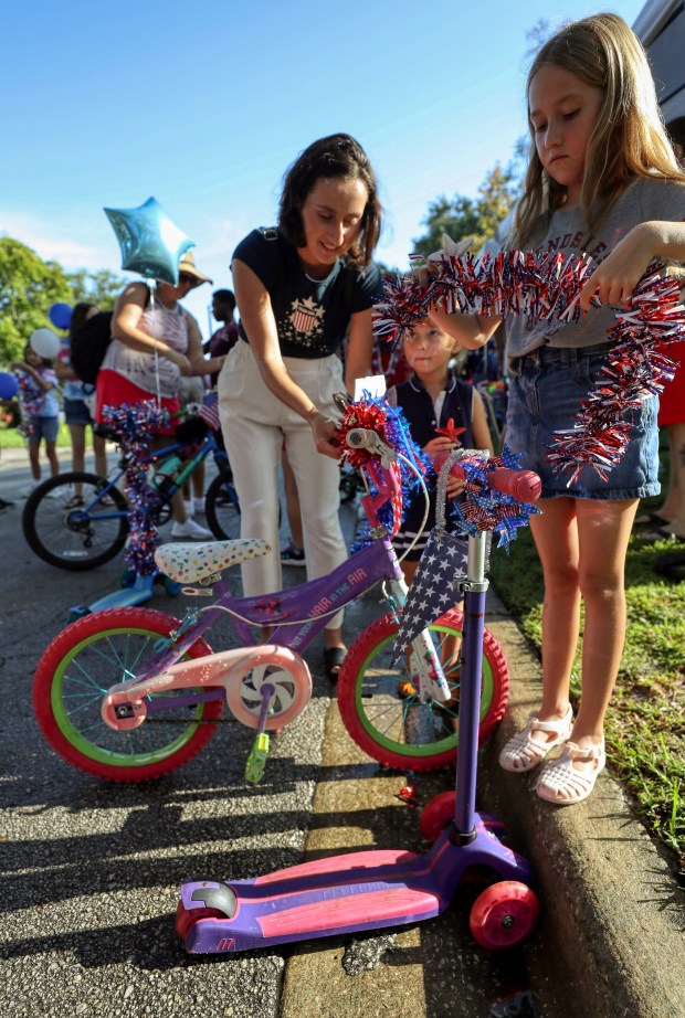 Mom Jana Melo helps Amanda, 4, with decorating her bicycle,...
