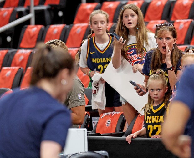 Fans hold signs as Caitlin Clark of the Indiana Fever...