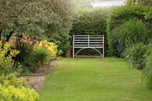 An English summer garden with a wrought iron white seat