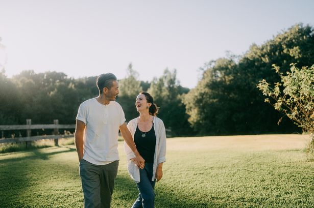 Cheerful couple walking on lawn at sunset