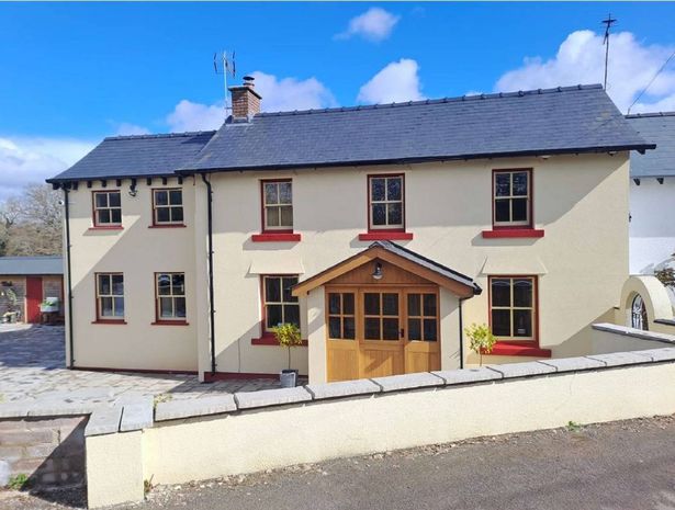 The image shows a large cottage in the rural location