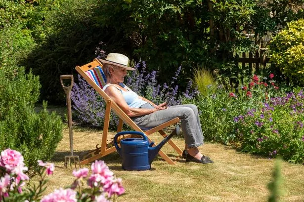 Woman taking a break from the gardening by sitting in a deckchair on a hot summer day