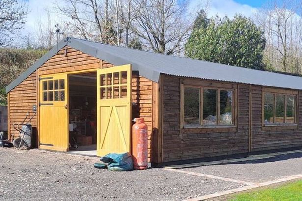 The image shows a huge shed, more like a bungalow, in the garden of a large property