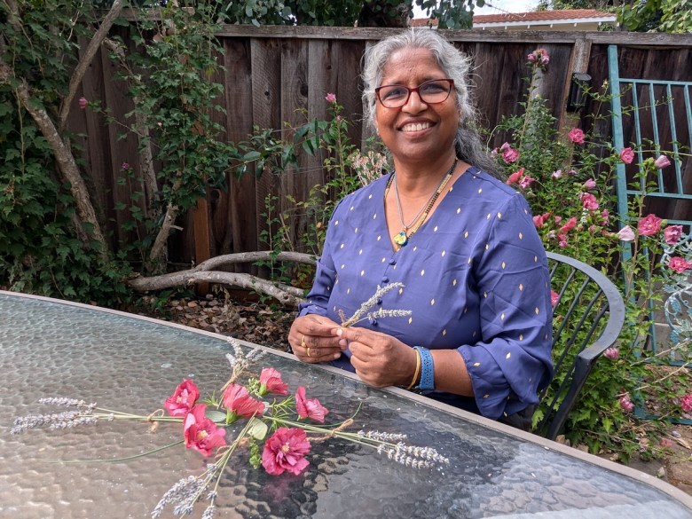 A woman sits in her garden working with flowers