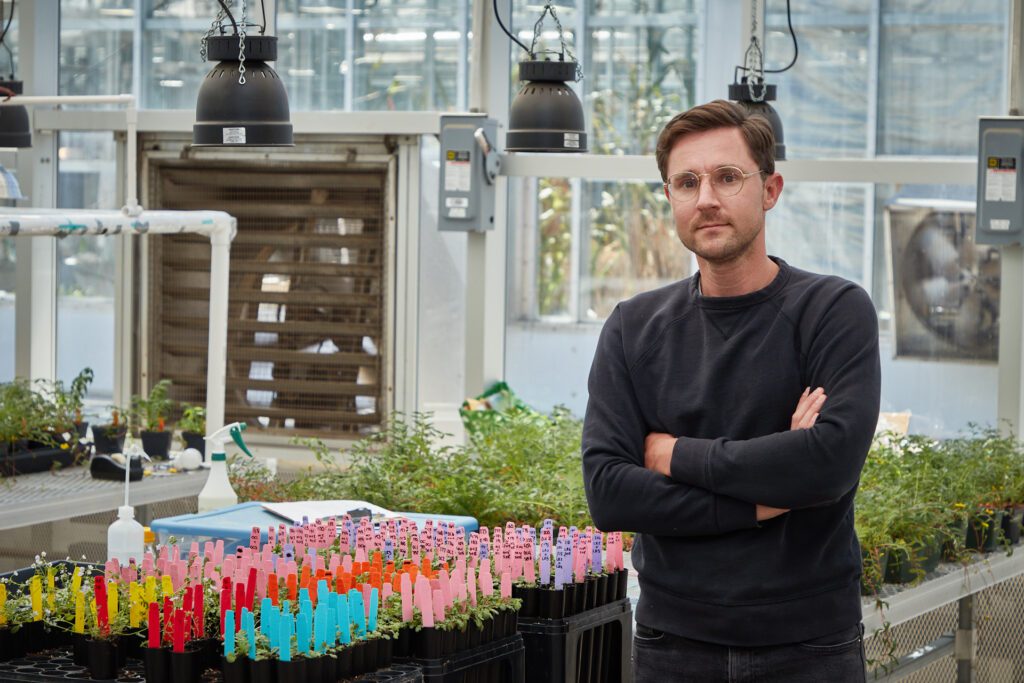 Man standing with arms crossed in a greenhouse
