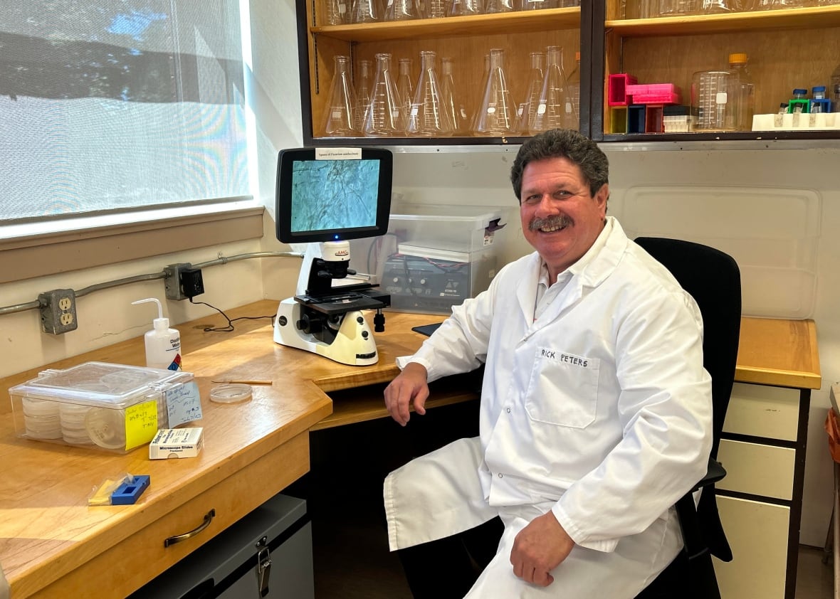 man sitting in a lap with microscope in front of him. 