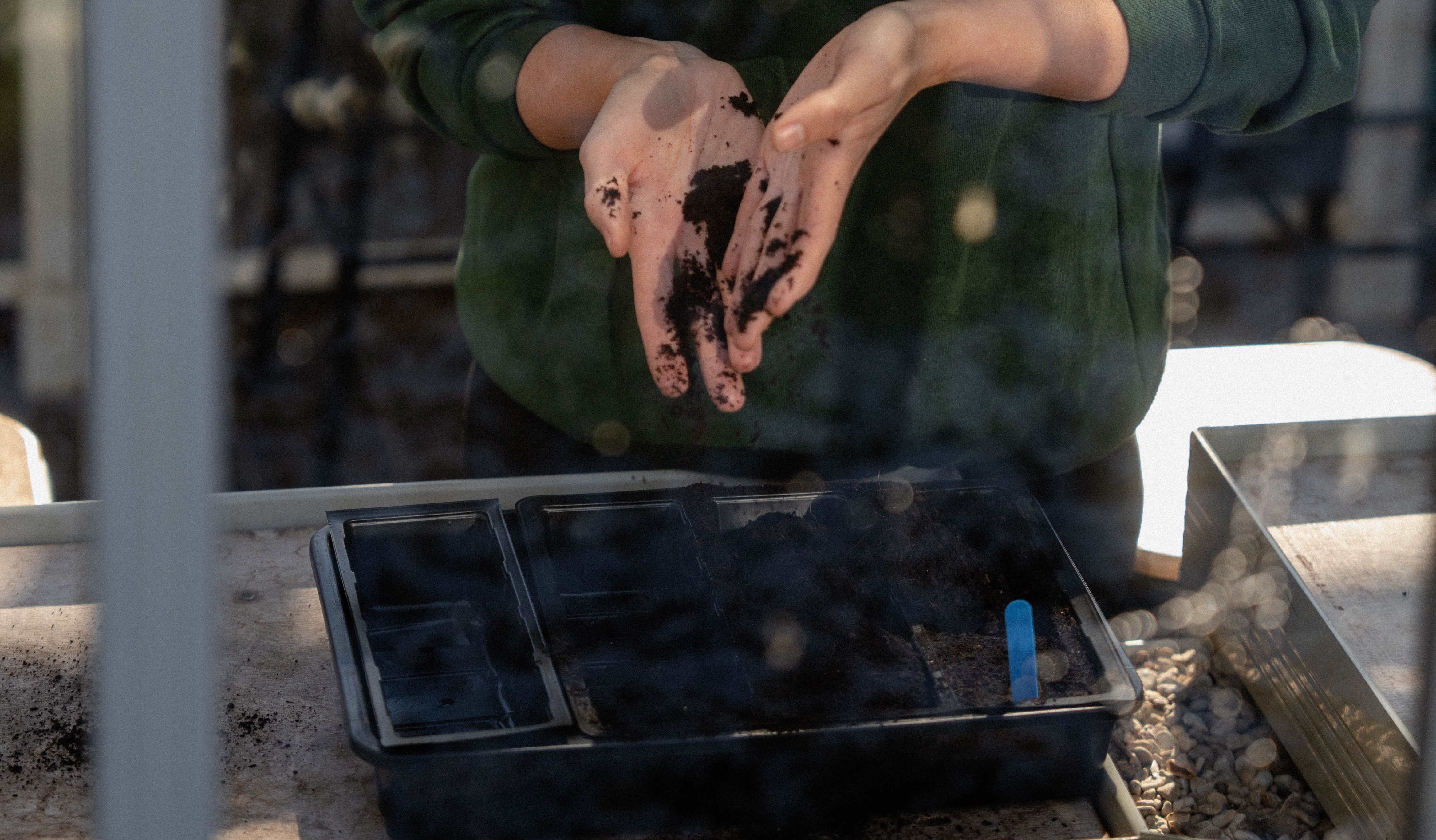 A woman examining soil in a gardening class.
