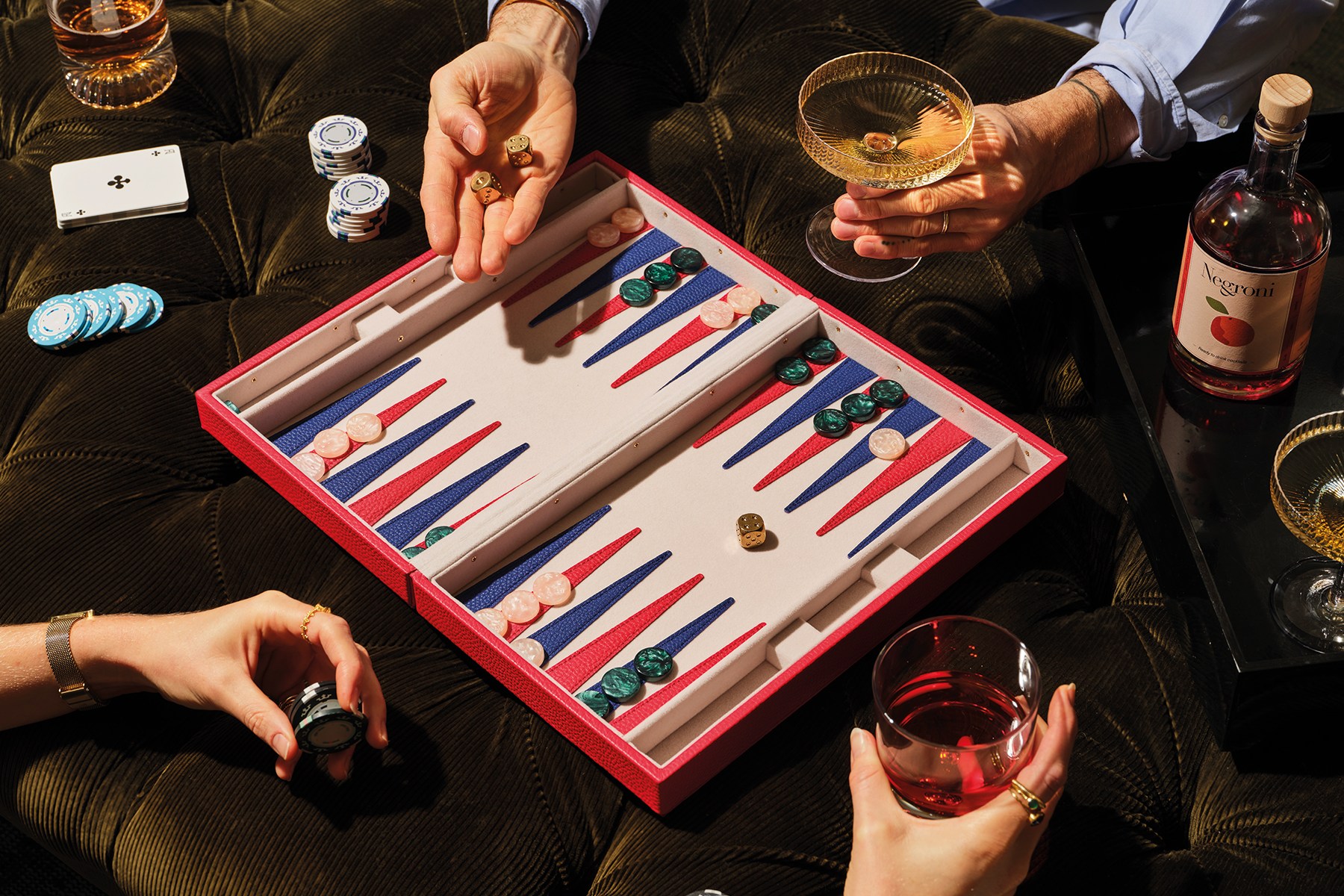 Two people playing backgammon with drinks.
