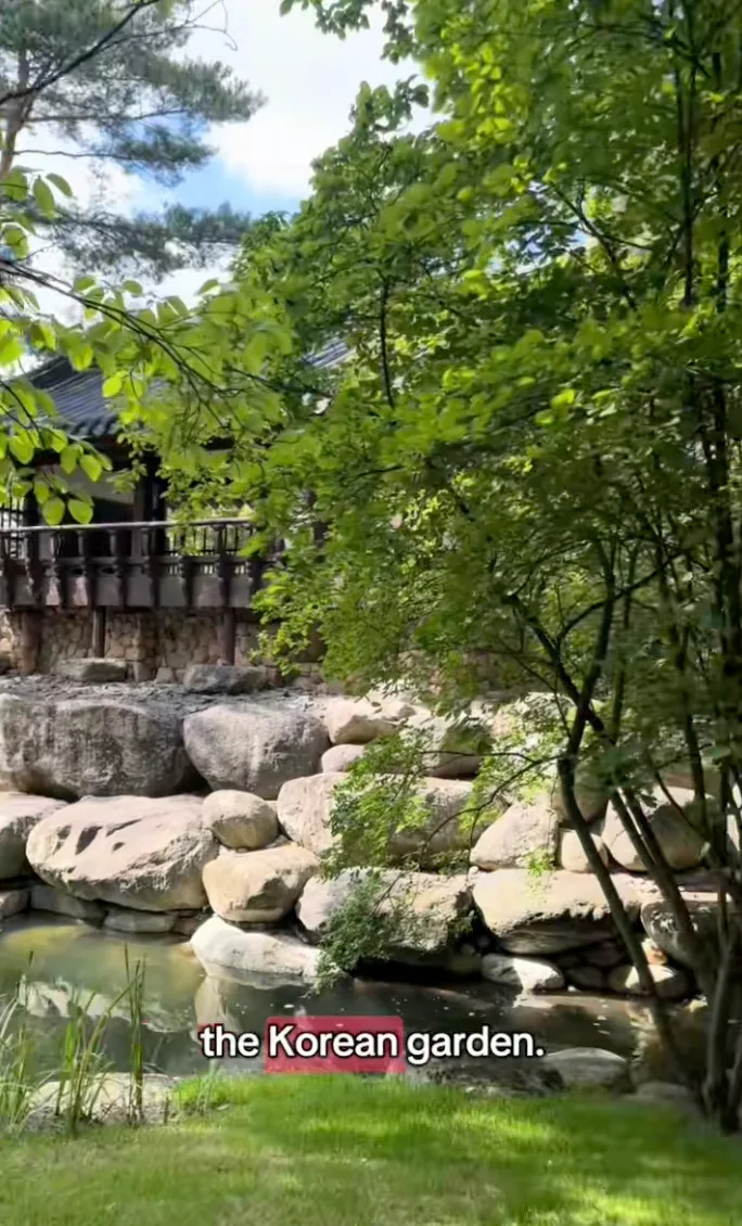 A serene garden with a wooden building, large stones, and a pond. Text: "the Korean garden."