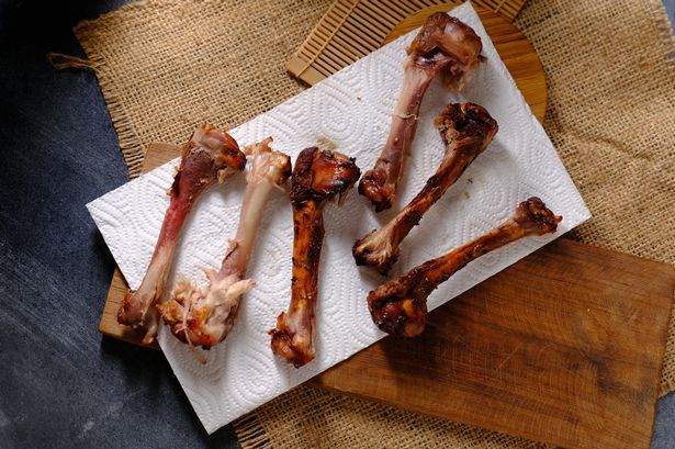 Grilled chicken bones on a white napkin on a wooden table