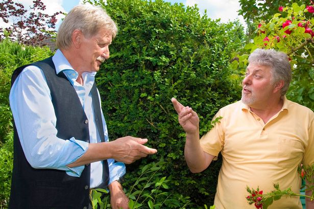 Two men argue in neighbour dispute taking place in a garden