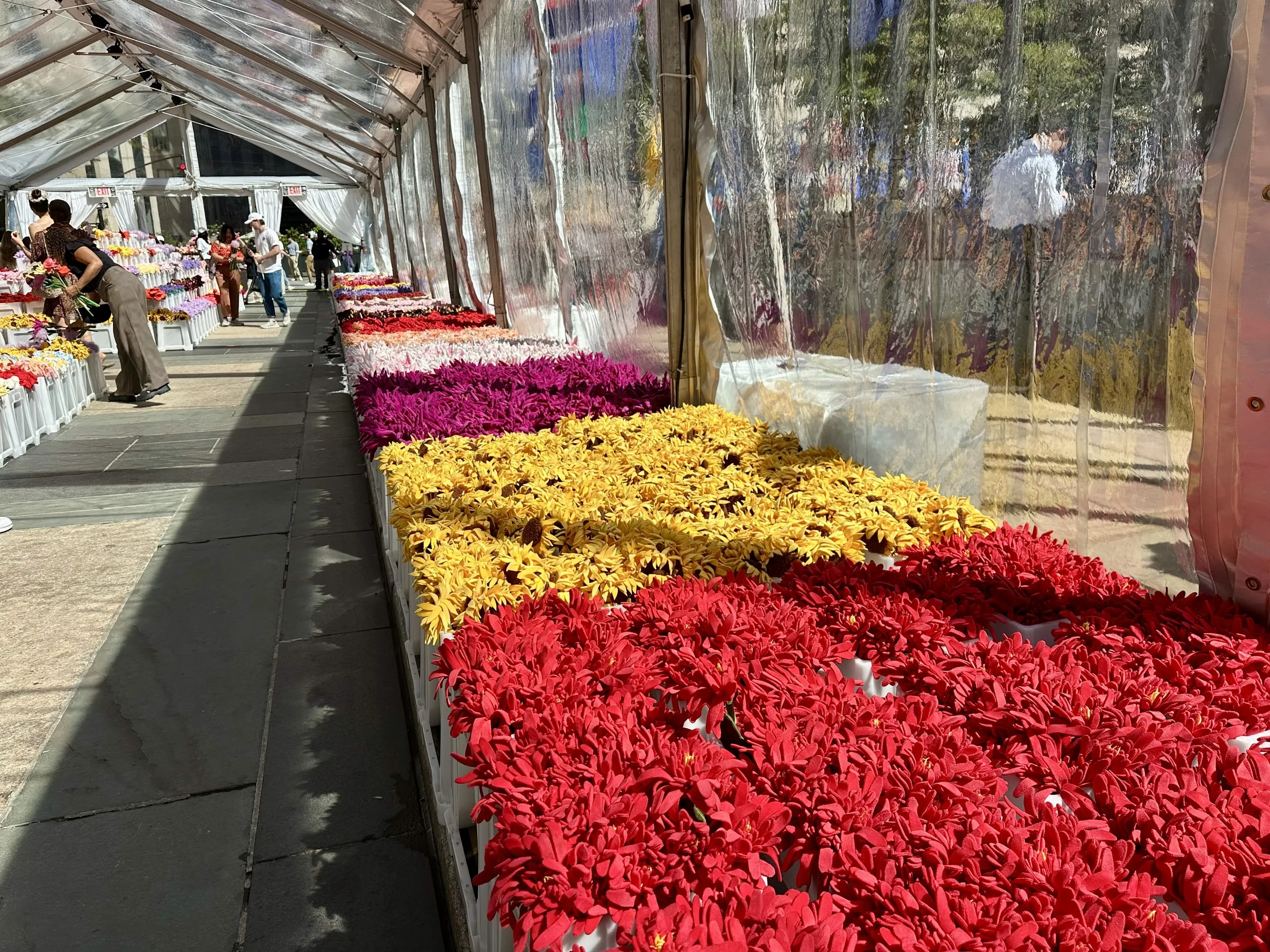 Crates of faux flowers inside a tent. 