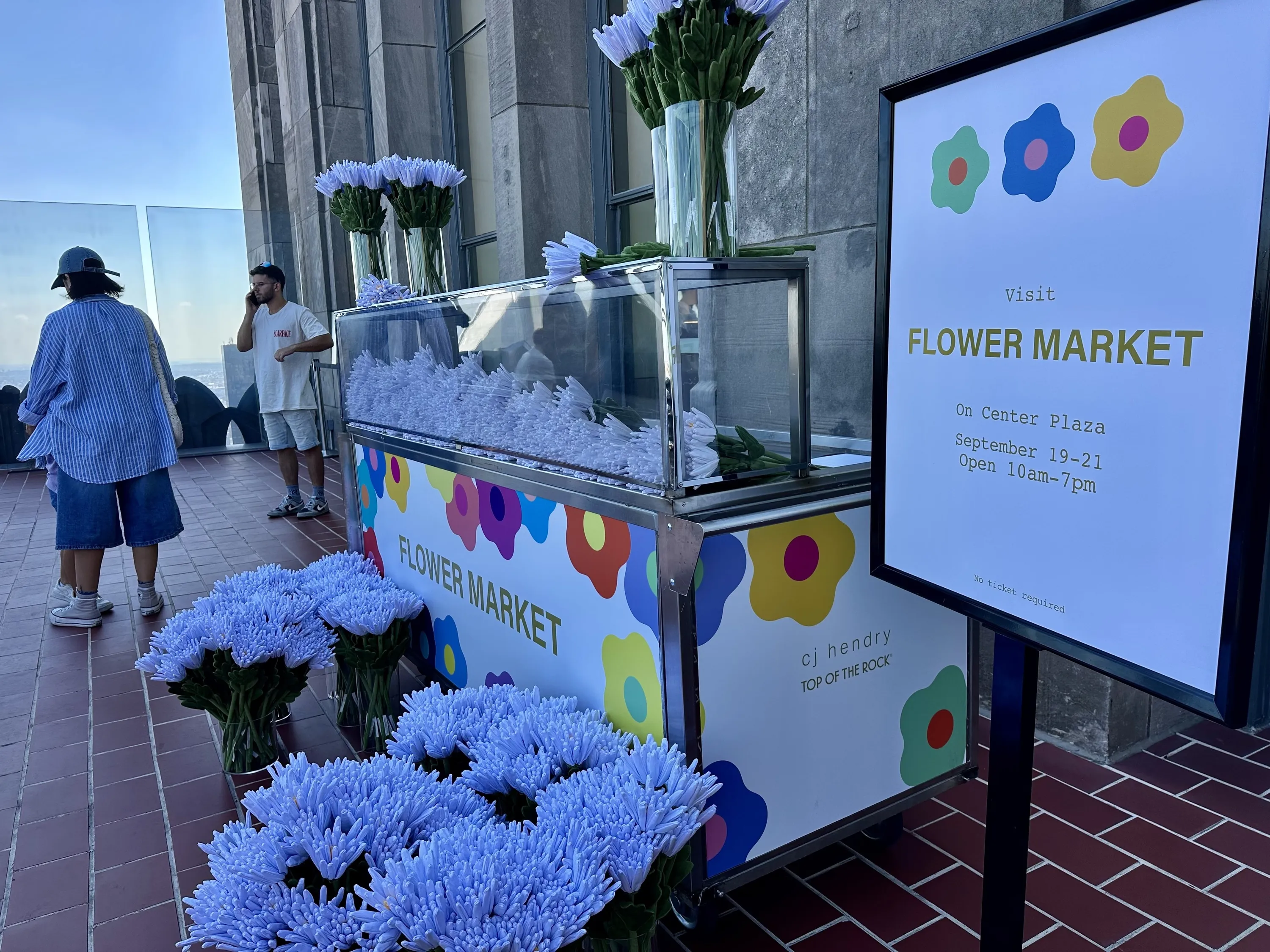 Bouquets of faux white flowers sit next to a display reading Flower Market.