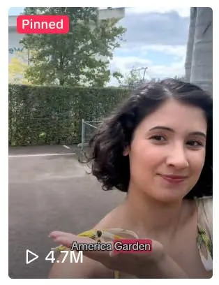 Person with short hair takes a selfie outdoors in a garden setting, smiling with hand extended. Image marked as pinned with 4.7M views