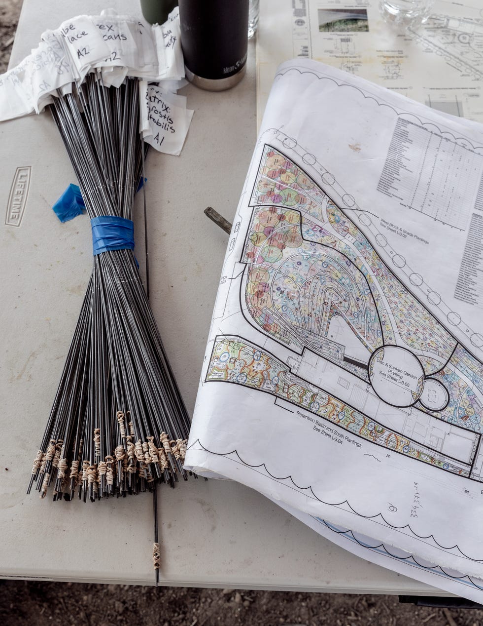 Blueprint and labeled rods on a table, indicating construction elements.