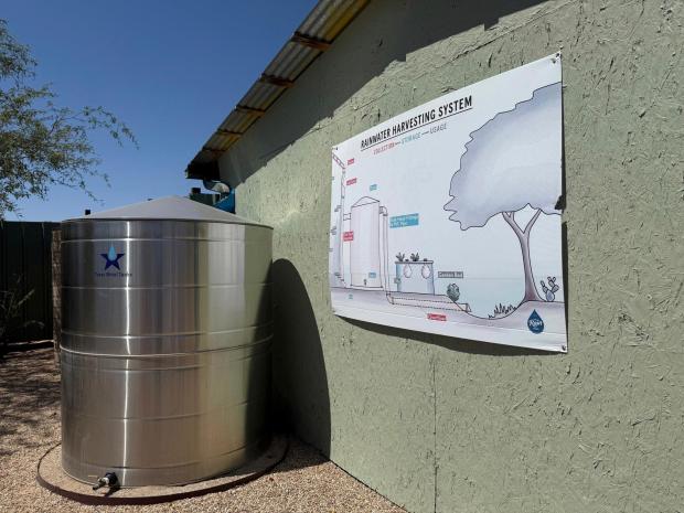 A new collection tank stands alongside a poster of a rainwater harvesting system outside The Rain Store in Tucson, Ariz., on June 27, 2025. (Anita Snow via AP)