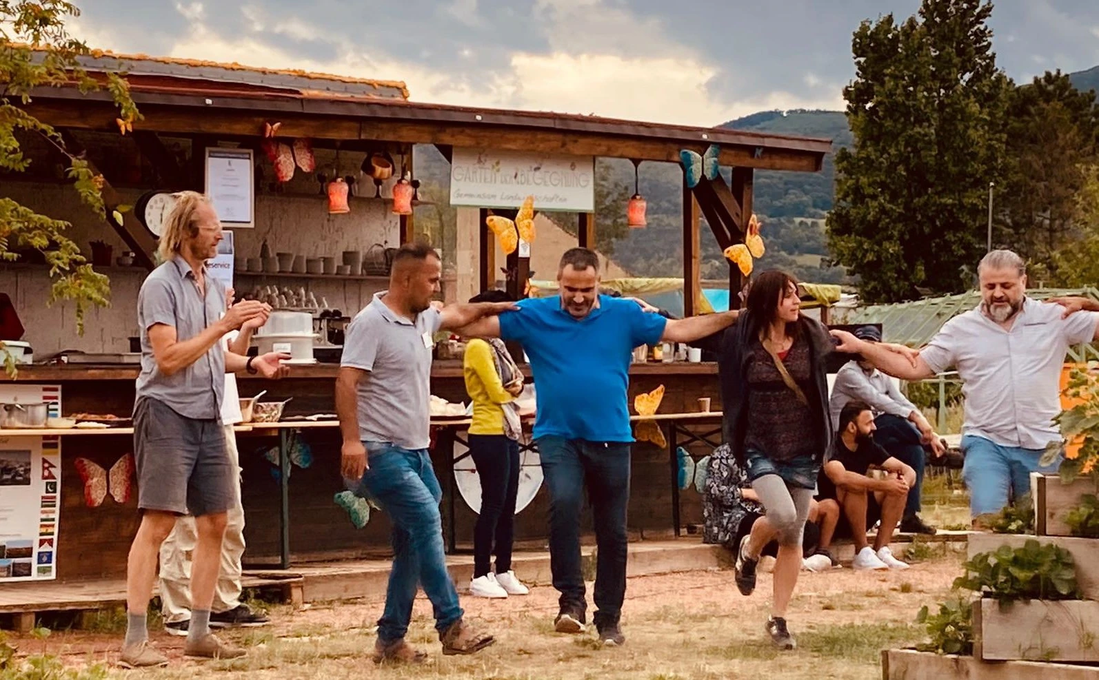 Co-founders Nikolai Ritter and Delshad Bazari (left and second to left) join in festivities at the Garten der Begegnung's open-air kitchen