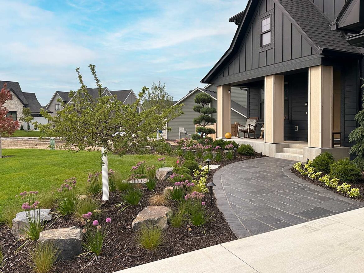 KG Landscape Paves the Way for Beautification That Is Built to Last and Designed to Live Sidewalk leading to house landscaped with flowers, rocks, and shrubs.
