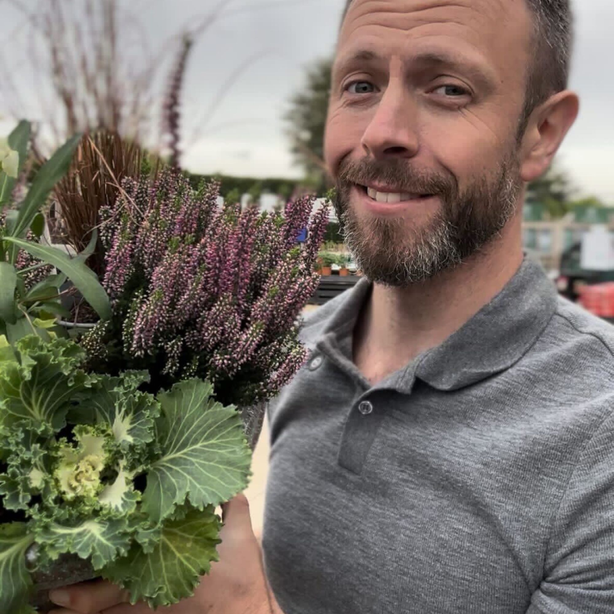 Adam Kirtland holding winter pot display with heathers and ornamental cabbage