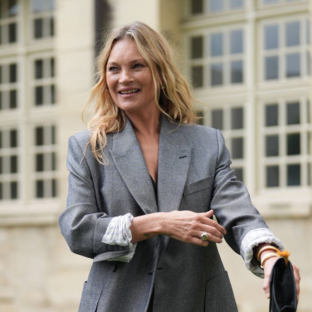 stylish individual in a tailored gray blazer and layered cuffs