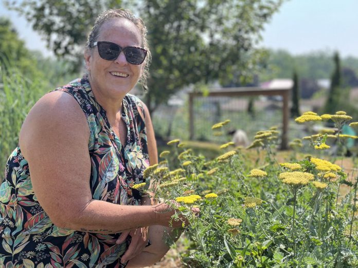 Elaine Day kneels in her rain garden in the east end of Peterborough. She took part in the City of Peterborough's Rain Garden Subsidy Program to help retain water for her vegetable gardens using natural methods. Elaine now enjoys the wildlife and pollinators the garden attracts. (Photo: Yvonne Hollandy / GreenUP)