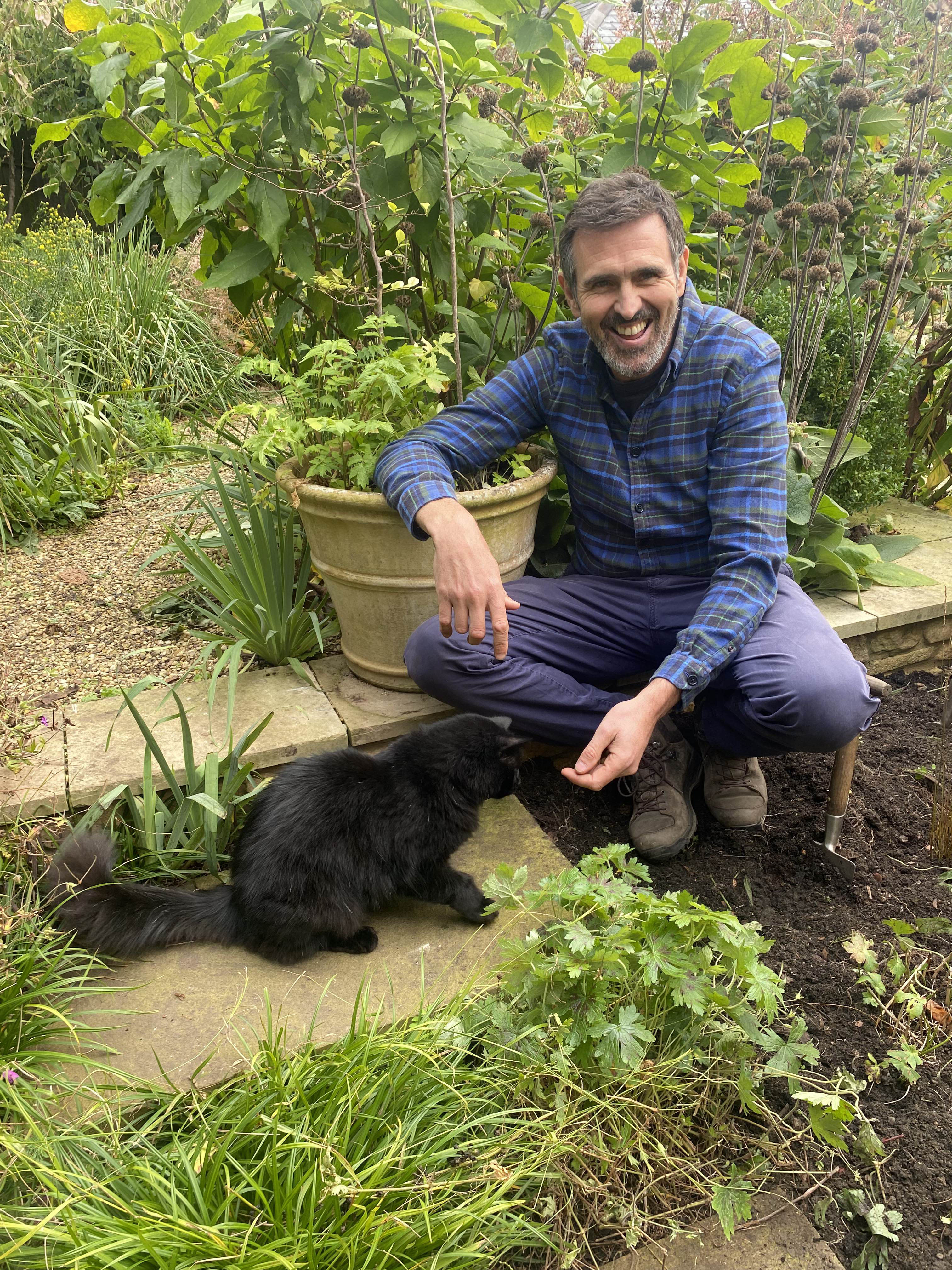 Adam Frost with Ash the cat in his garden.