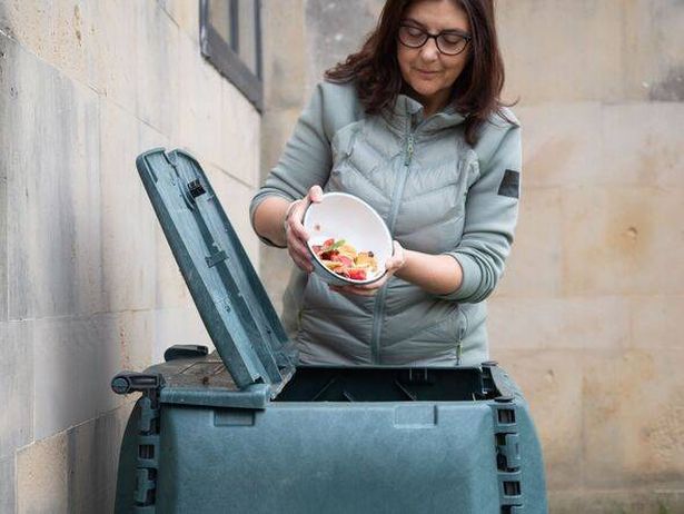 Woman throwing food scraps into compost bin for recycling