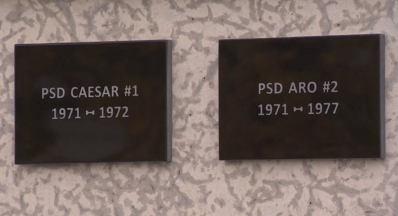 Square plaques on a stone column are inscribed with names