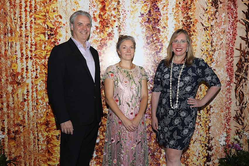 Rob Rominiecki, artist Rebecca Louise Law and Jennifer Rominiecki against a backdrop made from a photo of the exhibit.