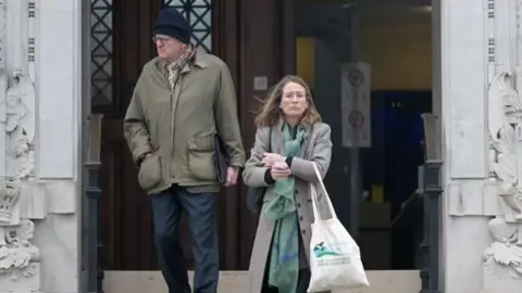 Wales News Service A woman and a man coming down steps outside Newport Crown Court. The man, on the left, wears dark blue trousers and a khaki coat, and a dark blue woolly hat. The woman, on the right, wears a grey coat and green patterned scarf; she carries a tote bag.