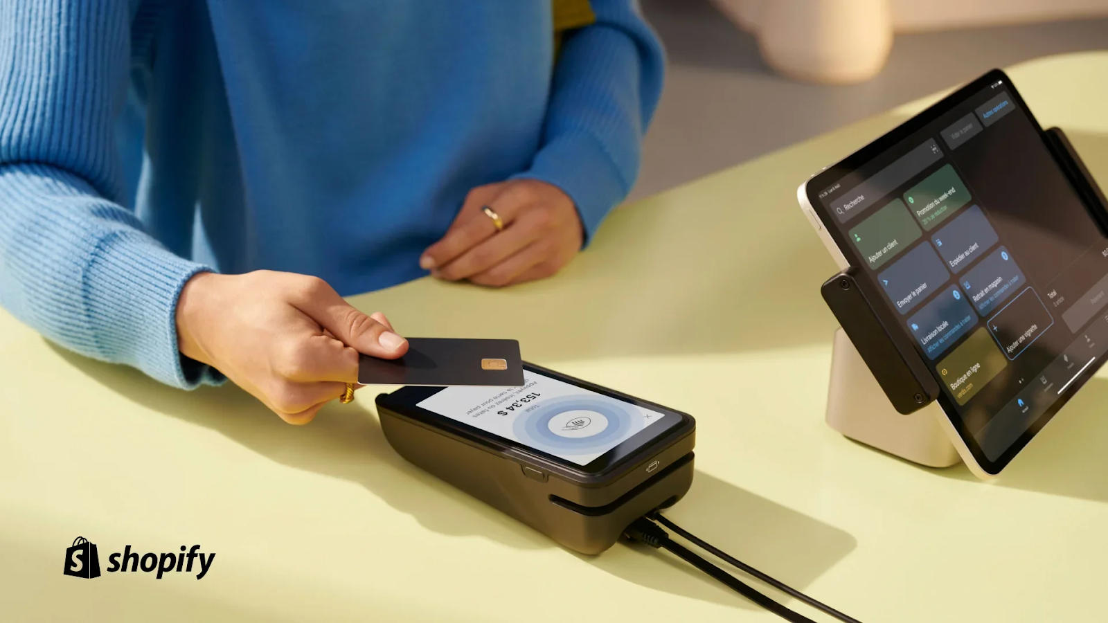 A person taps a credit card on a Shopify POS terminal to complete a purchase.