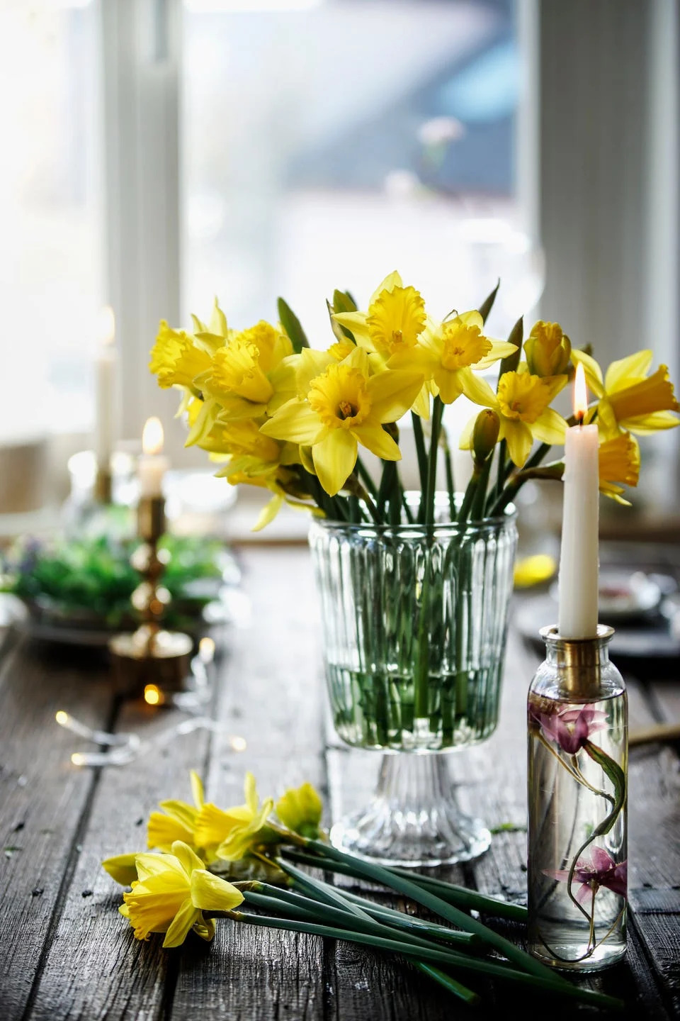 vase with beautiful yellow daffodils flowers bunch on wooden table at window. springtime lifestyle