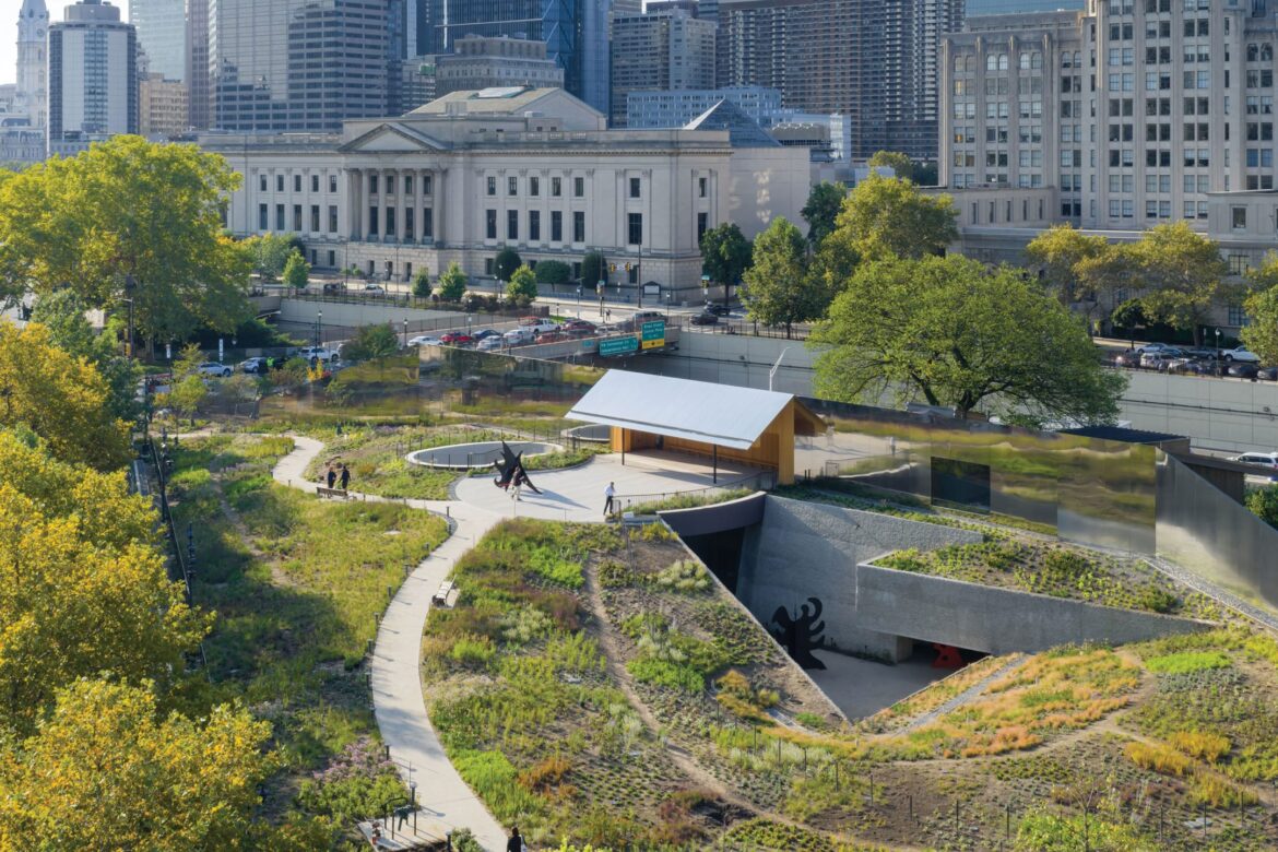 Explore the Newly Opened Calder Gardens in Philadelphia Urban park with winding paths, greenery, art installations, and city buildings in the background on a sunny day.