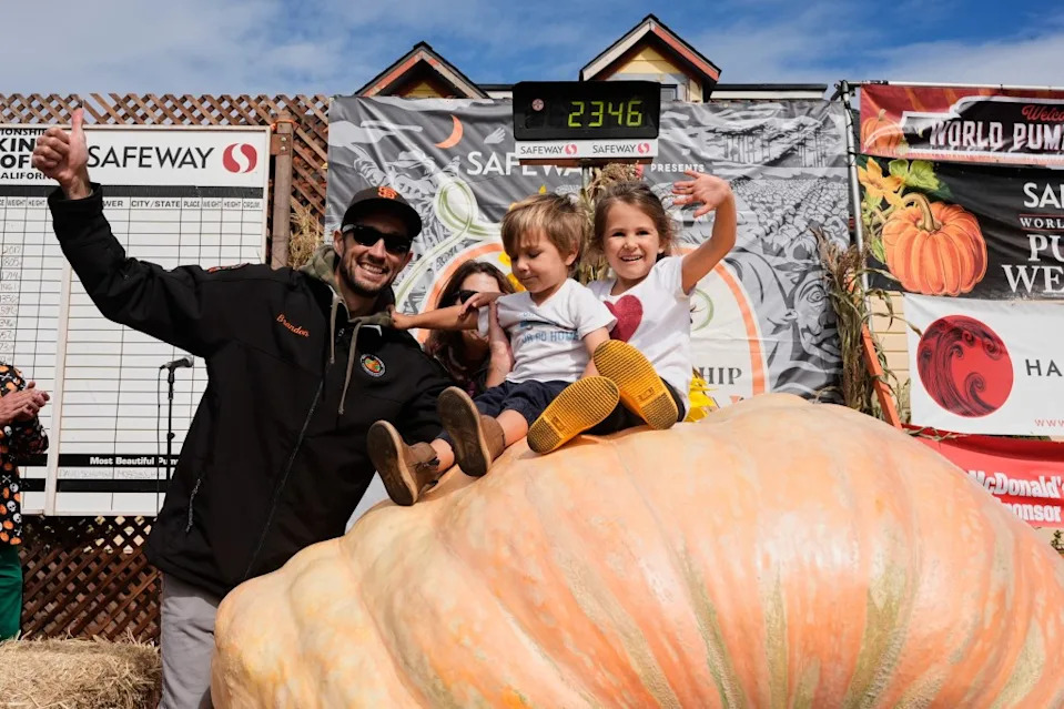 Brandon Dawson with his children Roman and Ayla on the giant pumpkin that won the contest. AP