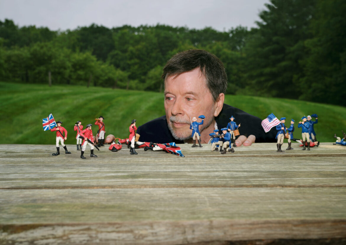 Ken Burns crouches by a table of toy soldiers