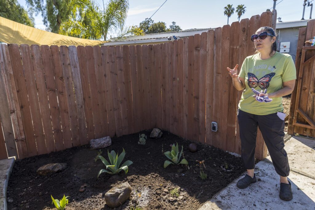a woman gives a gardening lesson in front of a yard