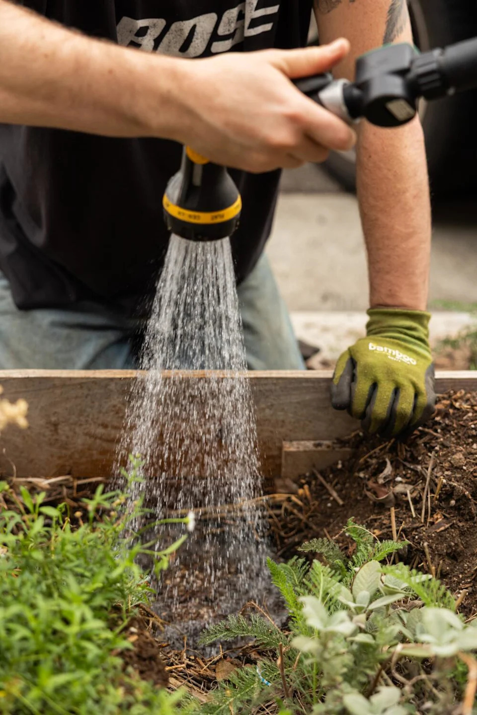Bex Muñoz waters a planting hole in a raised garden bed.