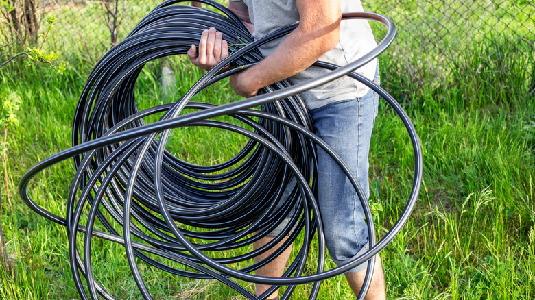 A man carrying irrigation hose