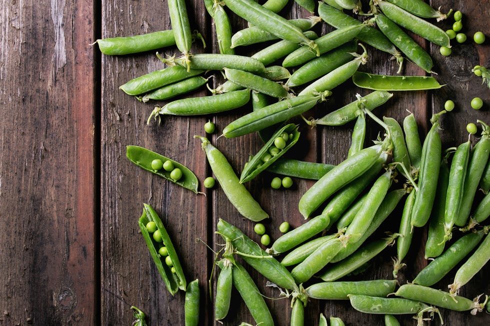 young organic green pea pods and peas over old dark wooden planks background. top view with space. harvest, healthy eating. (photo by: natasha breen/reda/universal images group via getty images)