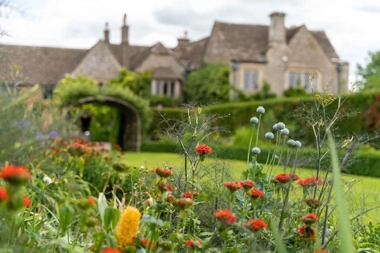 a garden featuring vibrant flowers with a vintage house in the background