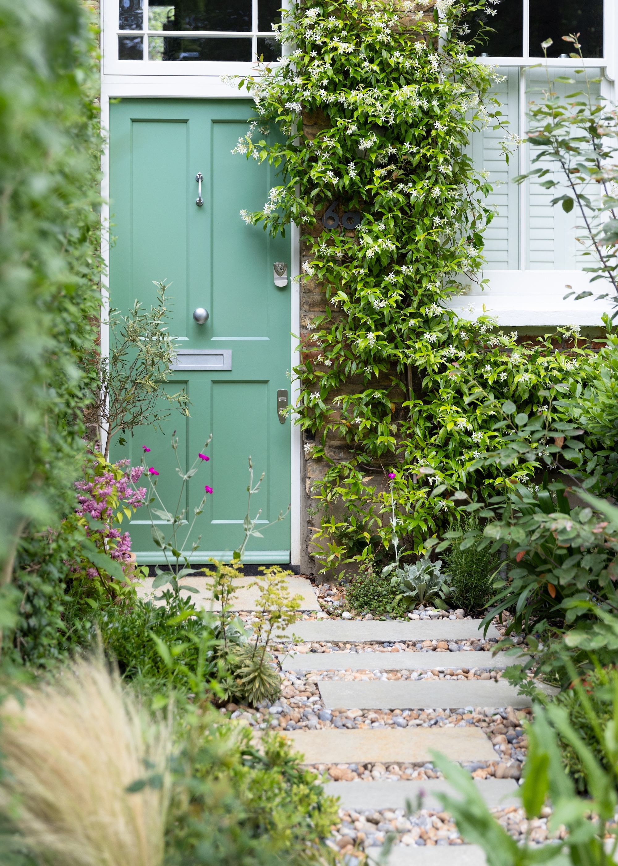 Green front door with garden path of staggered slabs and large gravel