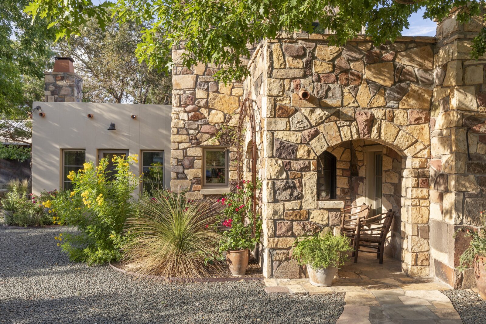 A garden in front of a stone house with long grass