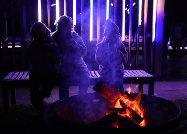 Children sip hot cocoa at a fire while attending the...