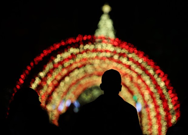 People stroll under colored arches on display for the holidays...