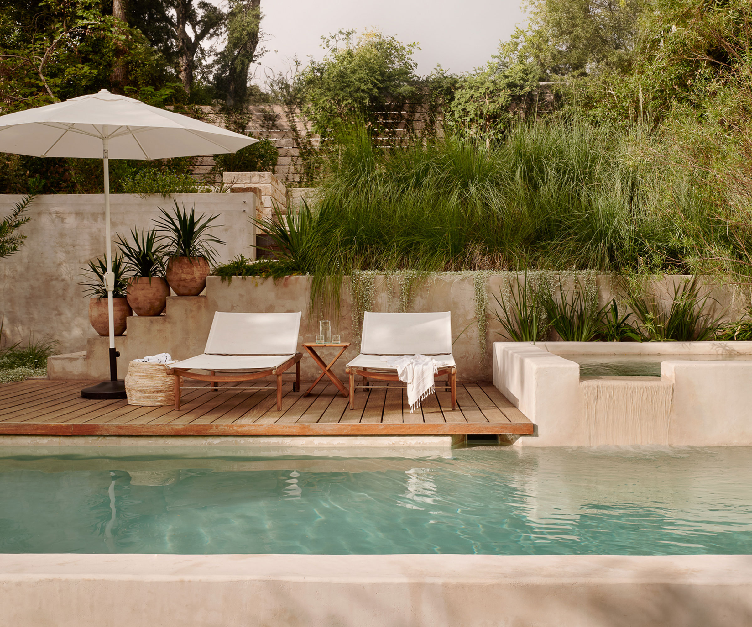 modern pool area with deck and planting in raised beds, sun umbrella and loungers