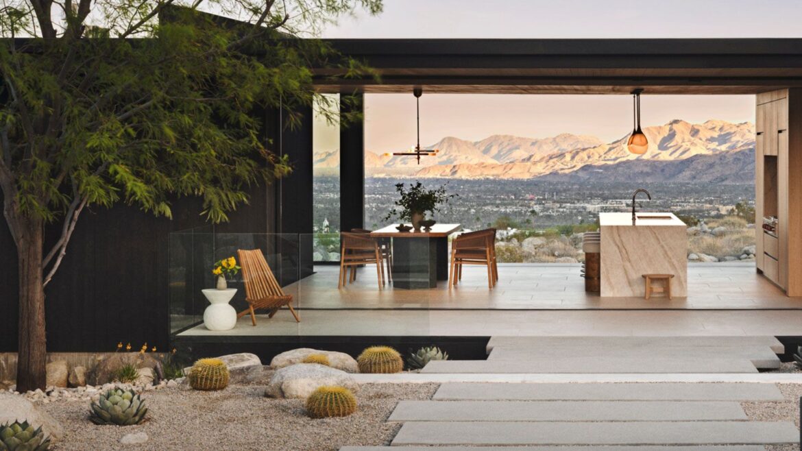 desert modernist landscaping design with rocks, gravel, plants and pavers, with a pergola and outdoor kitchen, and view to mountains beyond