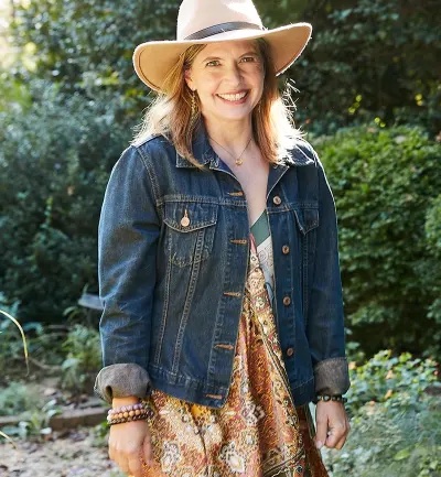 caucasian woman smiling to camera with a denim jacket and hat