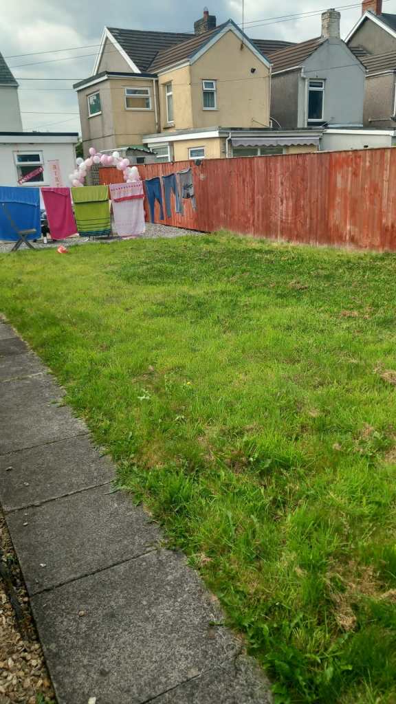 Backyard area with red fence and brick structure before Clive Jeffries’ garden transformation