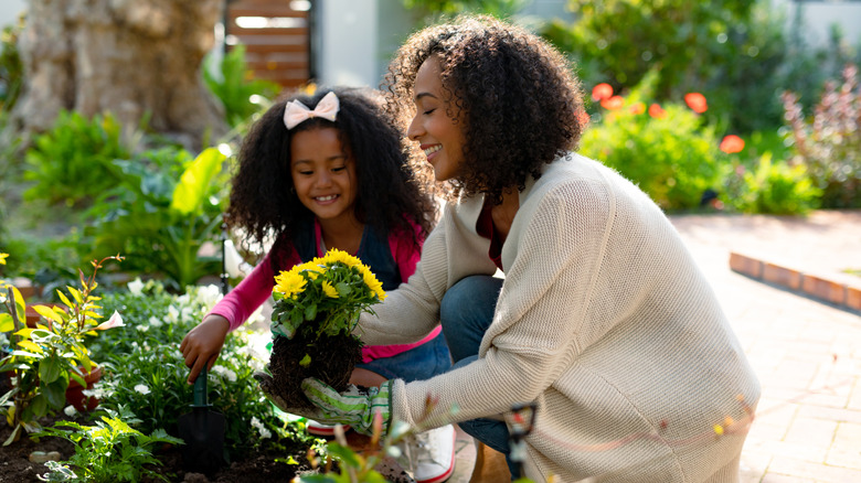 A mother and daughter planting flowers in a garden