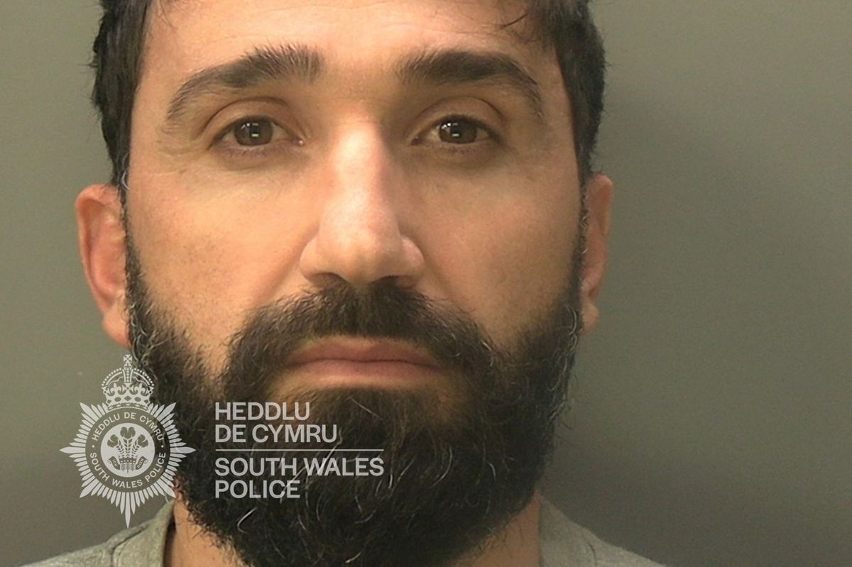 Custody photo of Kushi Alket, 35, who has black hair, a black beard and is wearing a grey tracksuit.